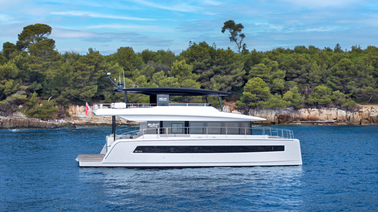 Solar-powered catamaran sailing in turquoise waters in a coastal location. Silent Grace Charter