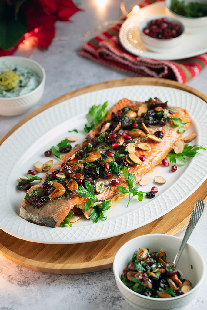 A cooked salmon fillet served in the center of a white ceramic plate.